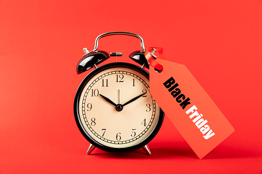 alarm clock on a red background, time for shopping. Black Friday