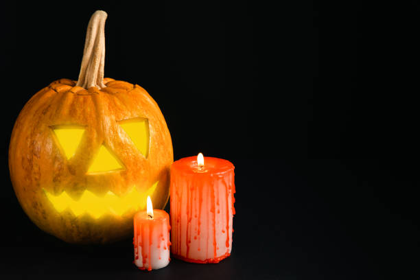 istock Halloween pumpkin on brown wood texture with candles. Composition on a dark background. Scary composition with glowing eyes and mouth. Holiday concept. copy space 1565728055
