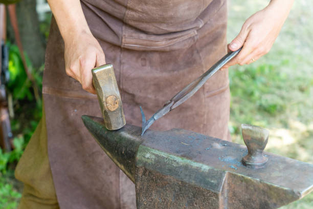 istock A blacksmith in a brown leather apron is forging a piece of iron on an anvil 1565728628