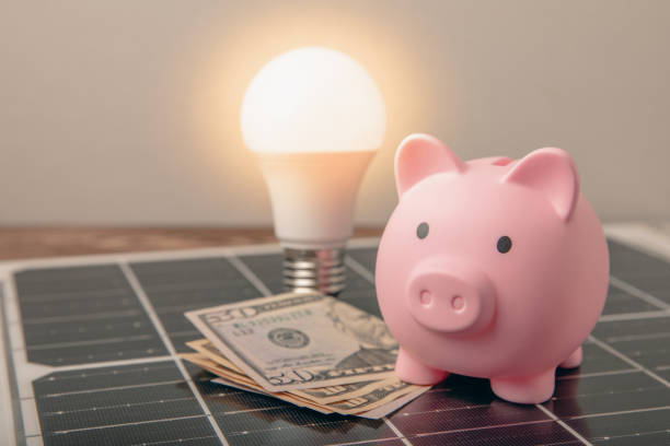 istock Flat lay composition with solar panel, led lamp and piggy bank on background. The concept of saving money and clean energy. The concept of ecology and sustainable development. 1565751244