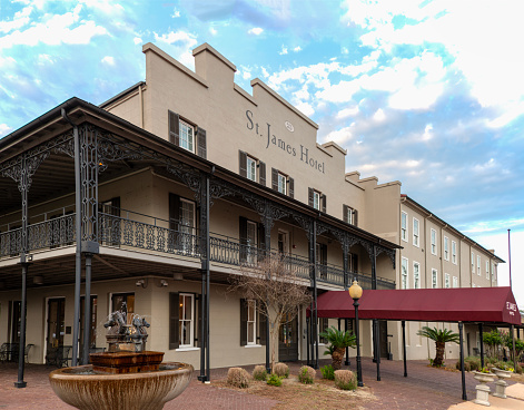 The St. James Hotel was built in 1837. The hotel facade includes original ironwork in the New Orleans French style. Interior rooms surround a courtyard with balcony walkways. Exterior balconies overlook the Alabama River and Water Avenue.\nSelma, AL USA\n07/20/2023
