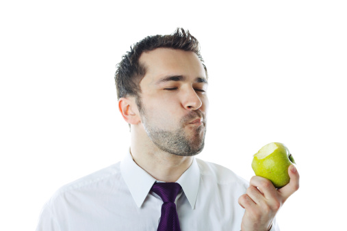 Close-up of  young businessman eating apple. Isolated on white.