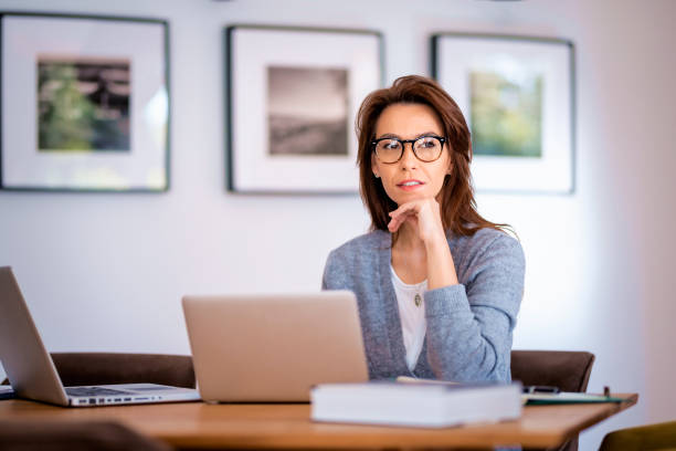 istock Attractive mid aged woman sitting at home and using laptops for work 1565874655