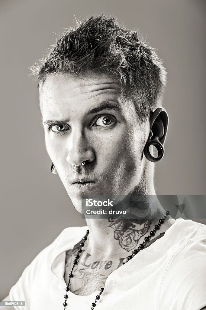 Portrait of a young male with tattoos Young male with tattoos pulling funny face. Studio shot. Making A Face Stock Photo