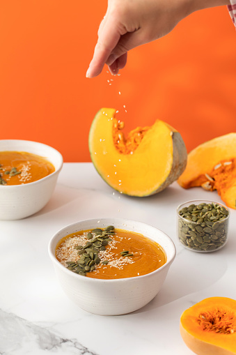 A plate with pumpkin soup puree, pumpkin and sesame seeds. The concept of the autumn menu. Easy vegetarian recipes, mashed soup.