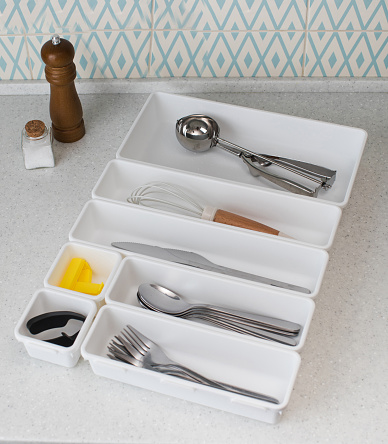 Plastic organizer trays with a set of cutlery on the kitchen table. The concept of a data storage system.