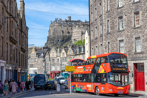 Edinburgh Scotland - June 3 2023: A Sightseeing Bus with Historic Buildings and the Castle in the Background in Edinburgh Scotland