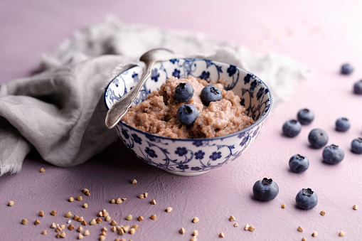 Cooked buckwheat with fresh blueberries and spoon.