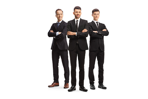 Three young businessmen in black suits posing isolated on white background