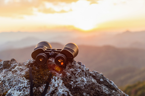 binoculars on top of rock mountain at sunset