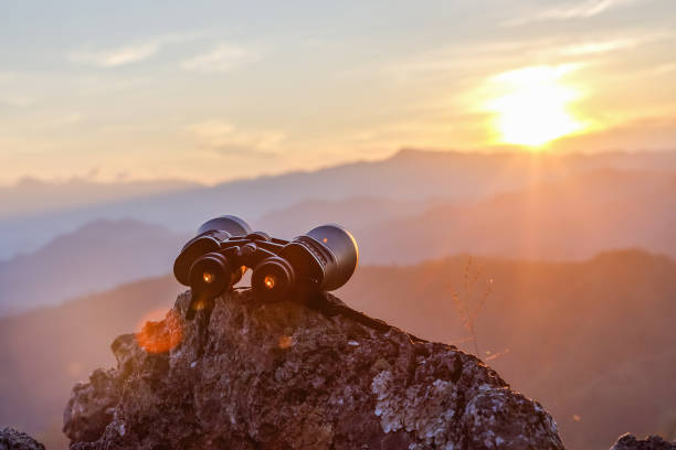 Binocular on top of rock mountain at sunset background