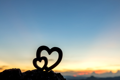 Silhouette Two Hearts on top of the rock mountain sunset background. Valentines day.