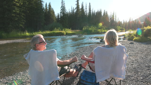 Senior couple talk while resting by creek edge