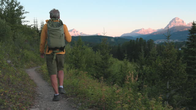 Senior man hikes along mountain trail at dawn