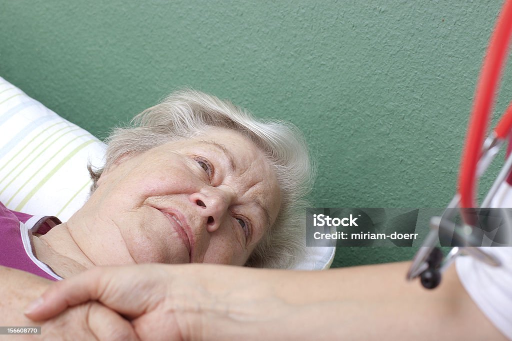 Medico accoglie paziente disteso nel letto - Foto stock royalty-free di 70-79 anni