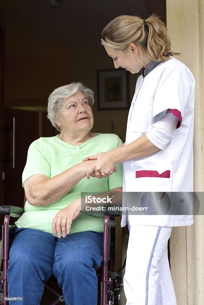 Pielęgniarka i starszy pacjent na wózku inwalidzkim - Zbiór zdjęć royalty-free (Opieka)