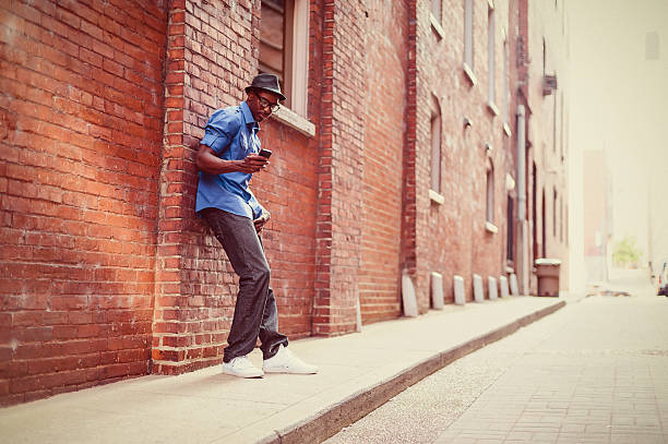 A young stylish man sends a text message on mobile phone outdoors.