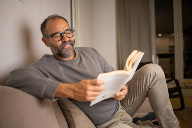 istock Happy mid adult man is reading a book 1566096723