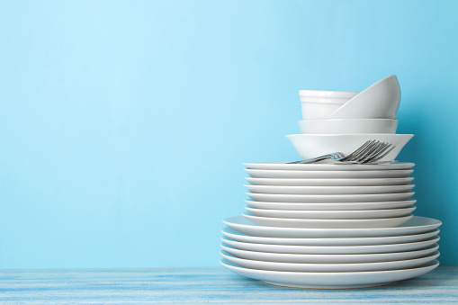 many different utensils. Tableware on a blue background. Clean tableware. various plates, bowls and cups.