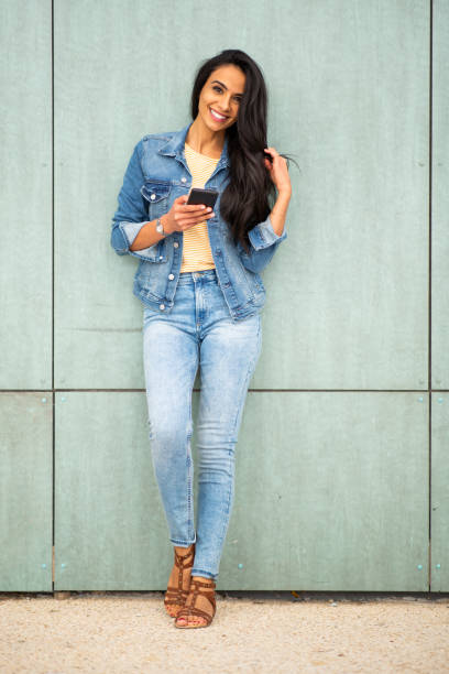 istock Pretty young woman with on mobile phone while standing against a wall 1566128442