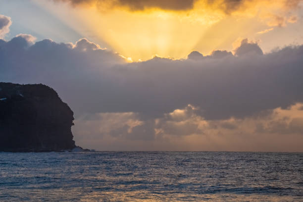 Sunrise with sunrays through the rain clouds at Macmasters Beach on the Central Coast, NSW, Australia.