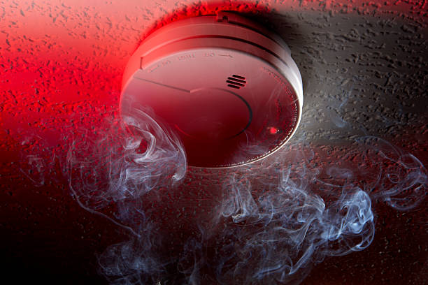Smoke detector Close up shot of ceiling mounted smoke detector with white smoke and red warning light smoke detector photos stock pictures, royalty-free photos & images