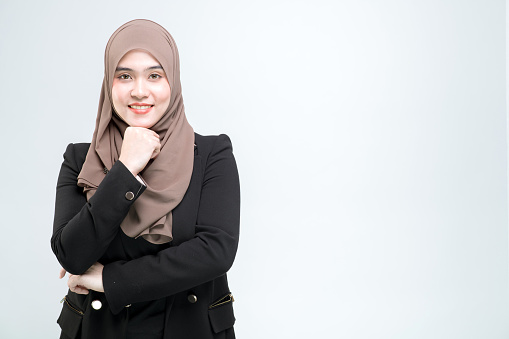 An office worker for an Asian Muslim woman stands with arms crossed with a happy face and a commitment to work, on white background.