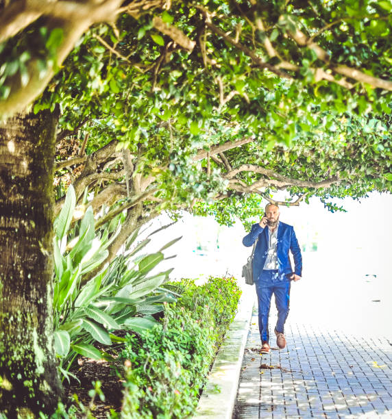 istock Man in a suit with briefcase using cellphone walking outdoors, headed to work, meeting, or a job interview 1566230440