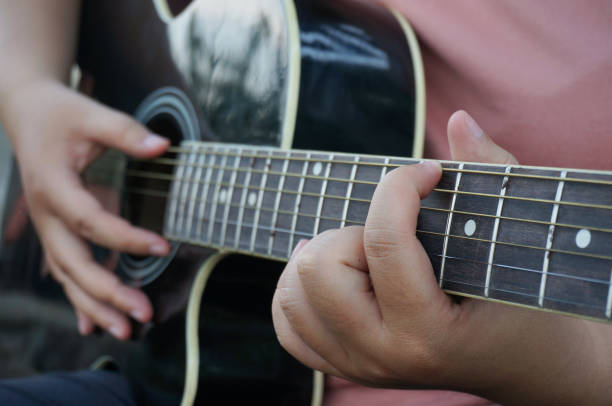 istock Young woman playing guitar at home. 1566266093