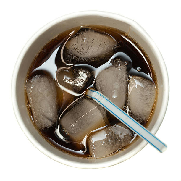 Overhead view of a glass full of soda with ice and straw An overhead view of a soft drink on ice with a straw in a paper cup on a white background. FL-photography stock pictures, royalty-free photos & images