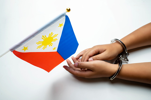 Human hand in handcuff with Philippines national flag on white background. Philippines independence day concept