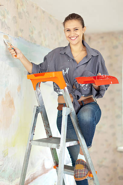 Happy woman paints wall Happy woman paints wall with brush Spalpeen stock pictures, royalty-free photos & images