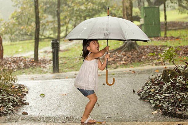 Menina brincando com Guarda-chuva na chuva - fotografia de stock