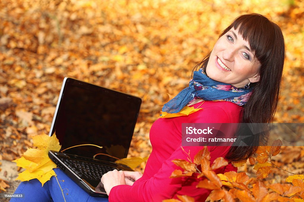 Donna con computer portatile in autunno parco - Foto stock royalty-free di Adulto