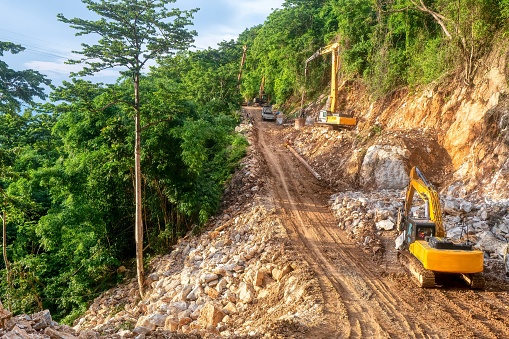 Pile drivers at work building the foundation for a new road through a steep, forested area on Mindoro Island, Philippines.
