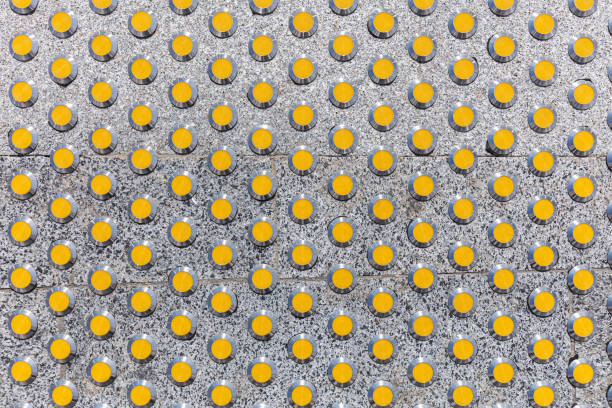 yellow tactile guide on grey granite sidewalk for visually impaired people