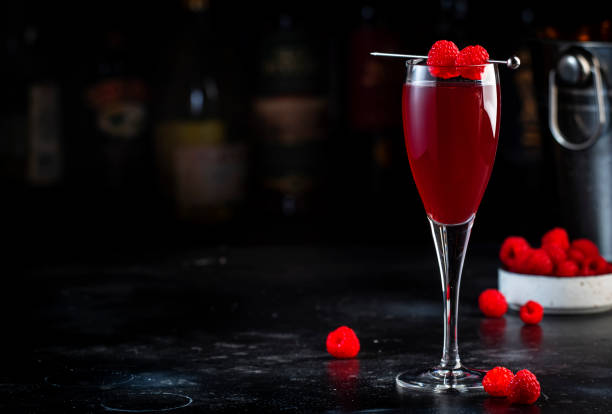 boisson cocktail alcoolisée rossini framboise avec prosecco, cava ou vin mousseux avec purée de framboise et glace, fond de comptoir de bar sombre, espace de copie - champagne cocktail raspberry pink photos et images de collection