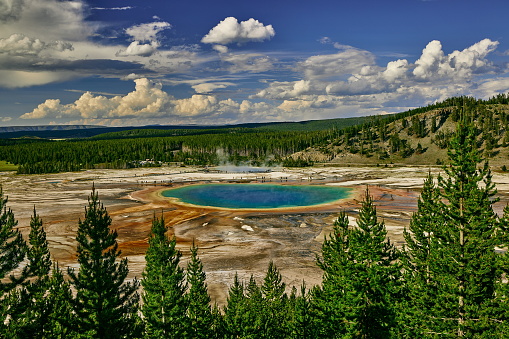 Man on a boardwalk looking at Beauty Pool hot spring in Yellowstone National Park