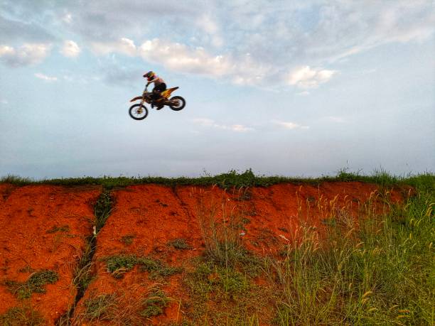 a motorbike racer is practicing by jumping over a hill