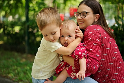 Mother and two children cuddling in a park