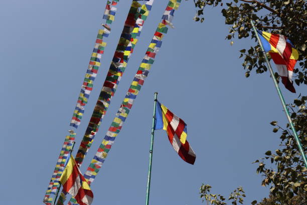 istock Flags hang on string line and pole on bright blue sky background, flags in a different of colors fluttering in soft sunny blue sky 1566490204