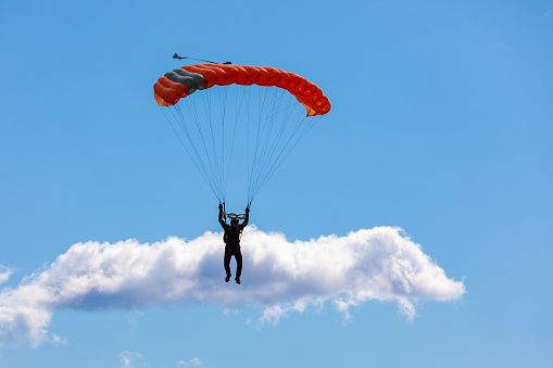 Woman parasailing in sunny day. She waves her hand in greeting.