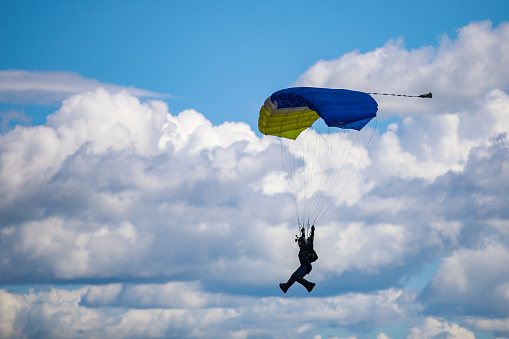 A female skydiver has jumped with a parachute and after the jump she picks up the parachute and carries it to the plane at the airport. She is happy and satisfied with the jump.
