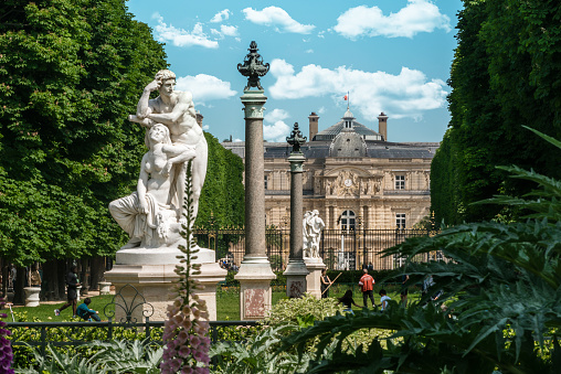 Paris, France - May 21, 2023: View of Luxembourg Palace from Luxembourg Gardens in Springtime. The Jardin du Luxembourg (known in English as the Luxembourg Garden, or Senate Garden) is located in the 6th arrondissement of Paris, France. Creation of the garden began in 1612 when Marie de' Medici, the widow of King Henry IV, constructed the Luxembourg Palace as her new residence. The garden today is owned by the French Senate, which meets in the Palace. It covers 23 hectares and is known for its lawns, tree-lined promenades, tennis courts, flowerbeds, as well as picturesque Medici Fountain, built in 1620.