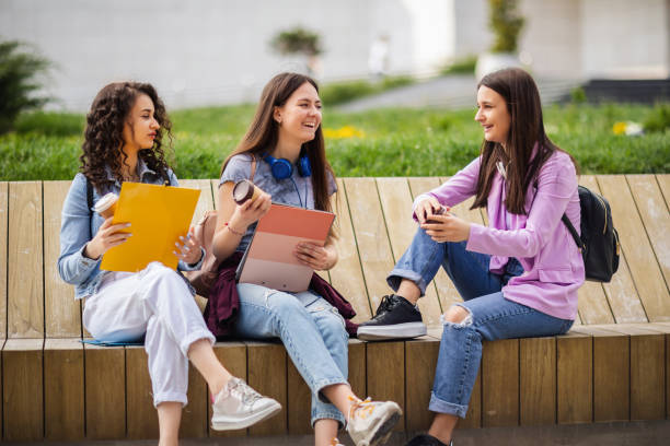 istock Group of collage students sitting on bench and studying for school 1566575311