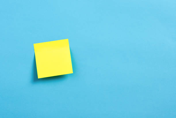 istock Blank or empty yellow sticky note paper on blue background. 1566579436