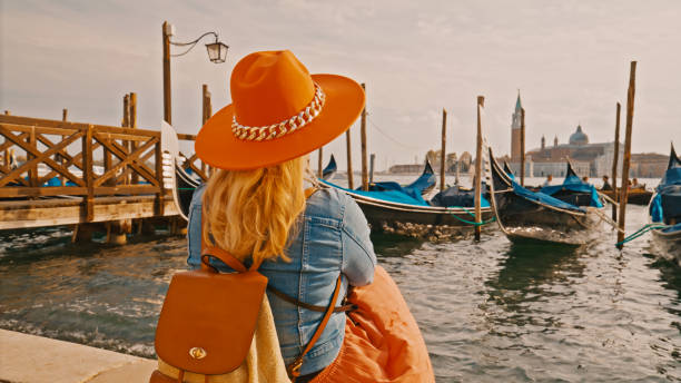 Rear view of woman wearing hat looking at gondolas on sea against sky during summer vacation