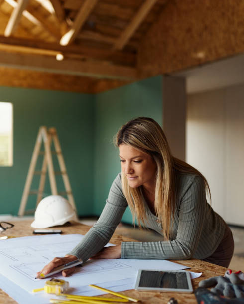 istock Young female architect analyzing housing plans at construction site. 1566581605