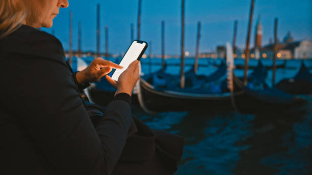 istock Woman using smart phone by sea during dusk 1566584652