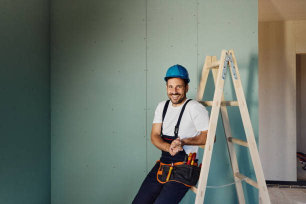 istock Happy construction worker relaxing on ladders inside of a built structure. 1566586328